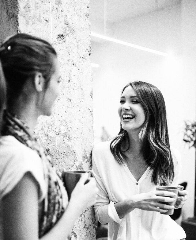 Women chatting with cups of coffee in hands