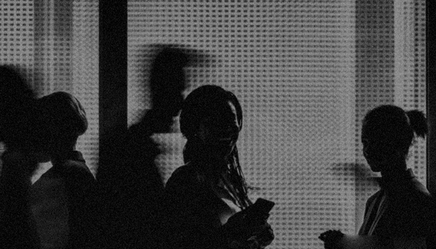 Silhouettes of people in front of some frosted glass.